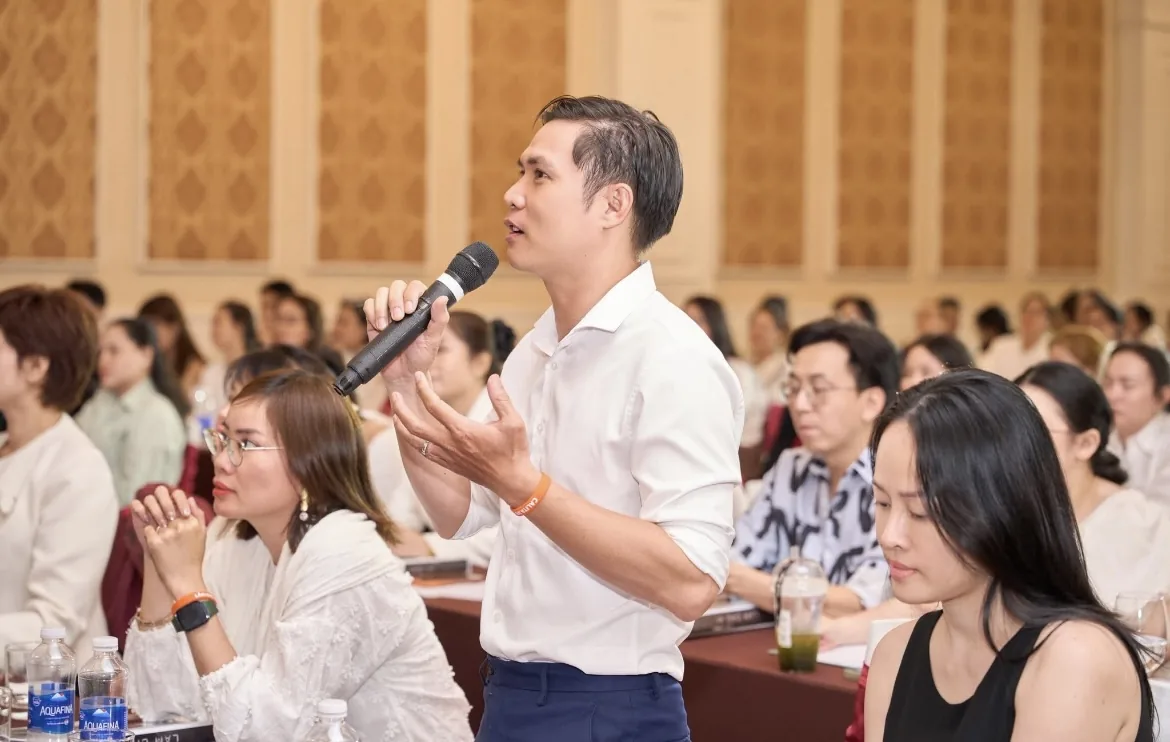 Học viên là chủ tiệm giơ tay hỏi lại một chi tiết về bỏ thuế khoán hộ kinh doanh 2026 trong buổi hướng dẫn, không khí tập trung