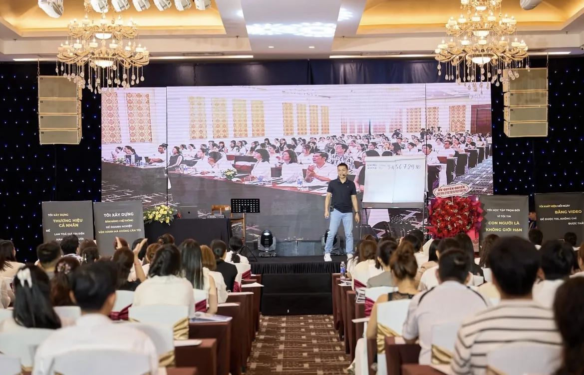 Học viên là chủ tiệm giơ tay hỏi lại một chi tiết về lệ phí môn bài hộ kinh doanh 2026 trong buổi hướng dẫn, không khí tập trung